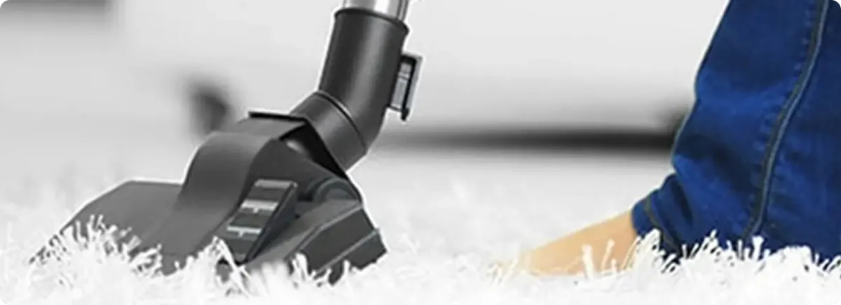 Close-up of a professional vacuuming a white carpet in Dearborn.